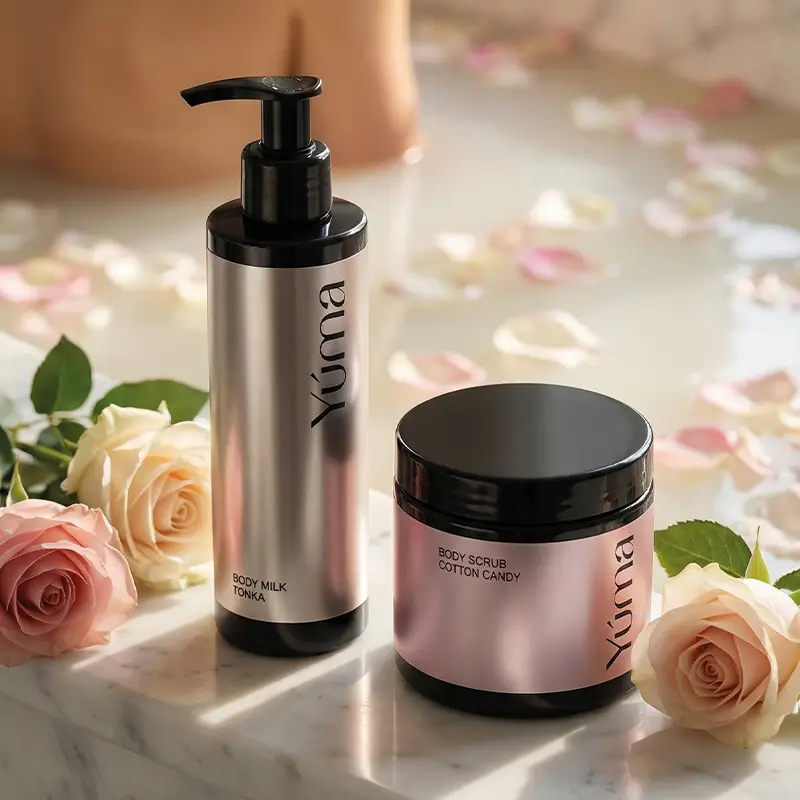 YUMA Body Care products next to roses, with a bathtub filled with rose petals in the background.