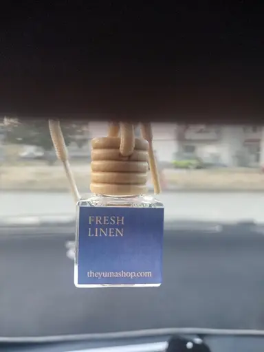 Fresh Linen car air freshener in a small glass bottle with a wooden stopper and rope.