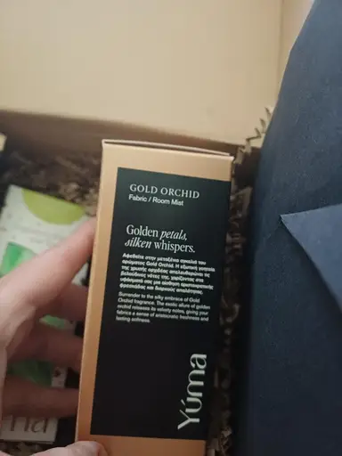 A YUMA Gold Orchid Fabric Room Mist paper box packed with protective tissue paper.