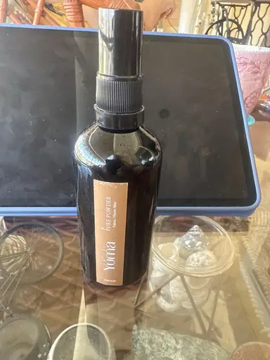 Dark glass YUMA Room Mist bottle with a brown label, placed on a glass surface.
