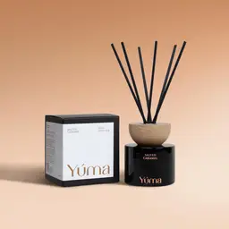 YUMA Salted Caramel reed diffuser in a black glass bottle with a wooden cap, next to its packaging.