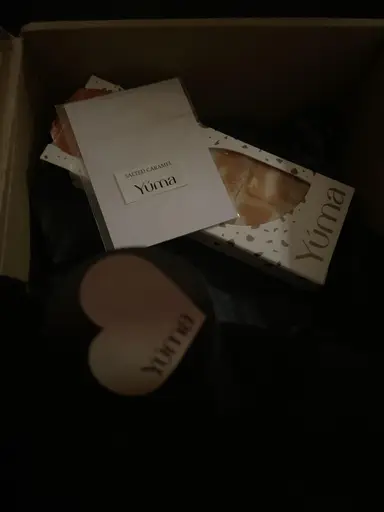 An open box of YUMA products, a white Salted Caramel card, and wax melt packaging against a dark background.