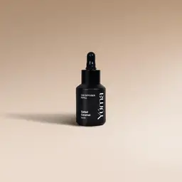 YUMA Salted Caramel black glass bottle with dropper on a beige background.