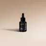 YUMA Salted Caramel black glass bottle with dropper on a beige background.