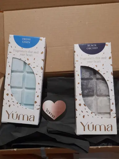 Two YUMA wax melt packages in Fresh Linen and Black Orchid scents inside a box.