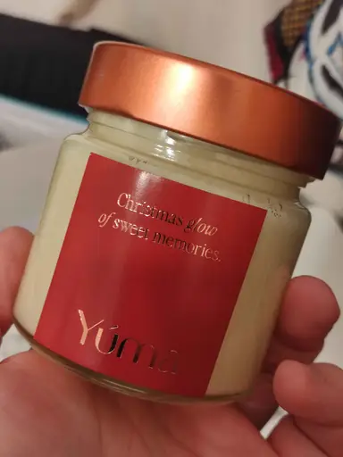 YUMA candle in a glass jar with a copper lid and red label, held in a hand.