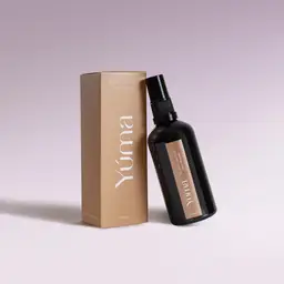 YUMA Black Orchid fabric mist in a black bottle next to its beige paper packaging.