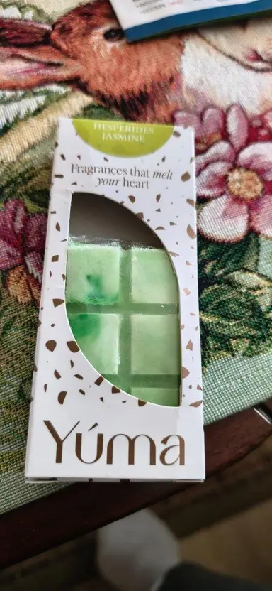 YUMA Hesperides Jasmine green wax melt in white packaging, placed on a fabric surface.