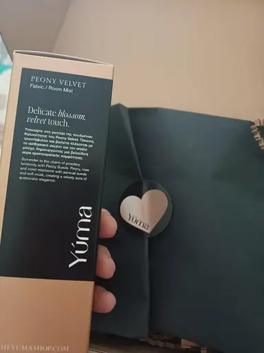 Close-up of YUMA Peony Velvet Fabric / Room Mist packaging next to a black box.