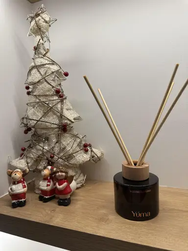 YUMA Melomakarono reed diffuser next to a decorative Christmas tree and small figurines.