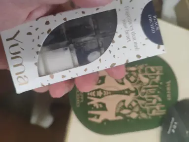 A hand holding a YUMA Black Orchid wax melts box over a green card.