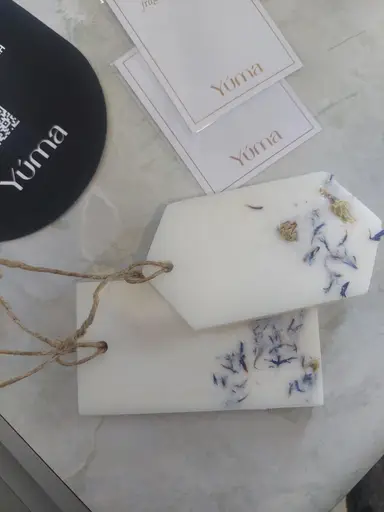Two white wardrobe sachets with dried blue petals and twine next to YUMA cards.