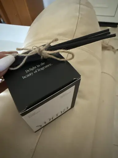 Black square YUMA box with black room fragrance sticks tied together with twine.