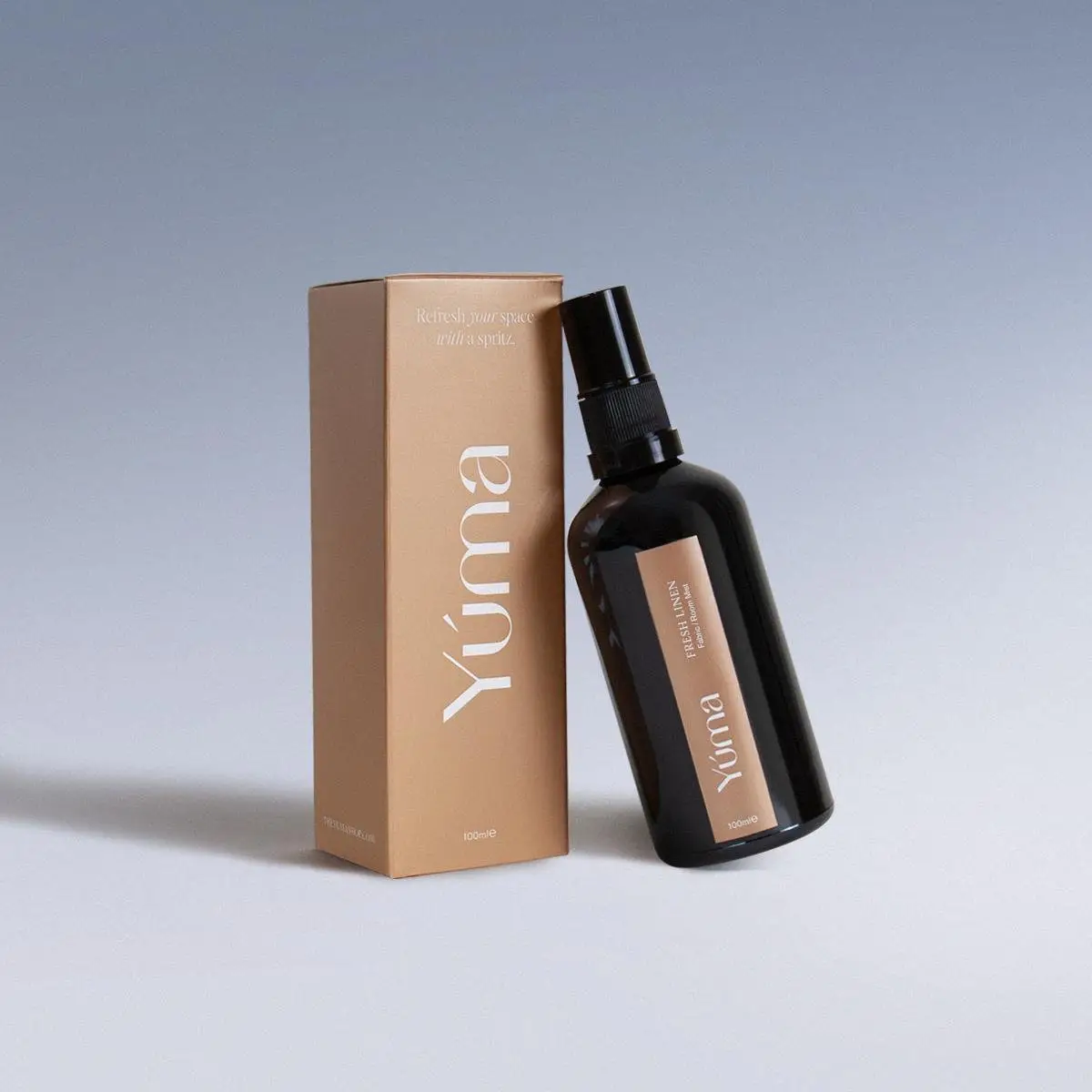 YUMA Fabric Mist in a dark glass bottle next to its beige paper packaging.