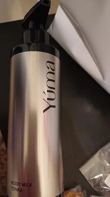 YUMA Tonka Body Milk metal bottle with a black pump, on a dark surface.