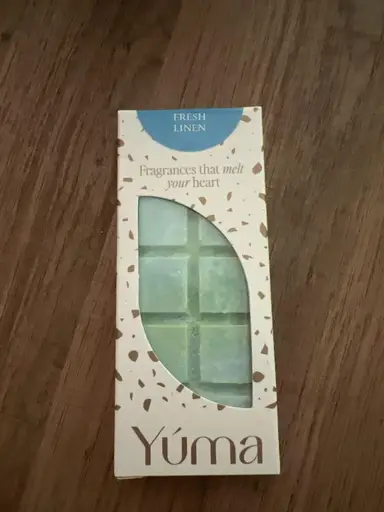 YUMA Fresh Linen wax melt packaging with light blue wax cubes on a wooden surface.