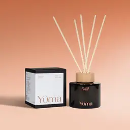 YUMA Orange Spices reed diffuser in a dark glass bottle next to its packaging.