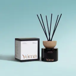 YUMA Laundry Nostalgia reed diffuser in a black glass vessel next to its paper packaging.