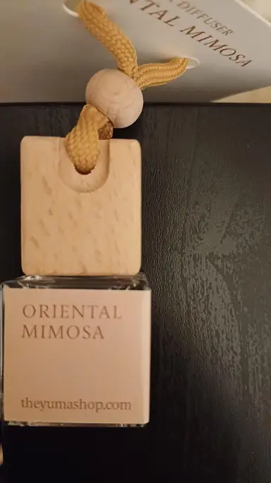 Small glass Oriental Mimosa car fragrance bottle with a wooden cap and yellow cord.