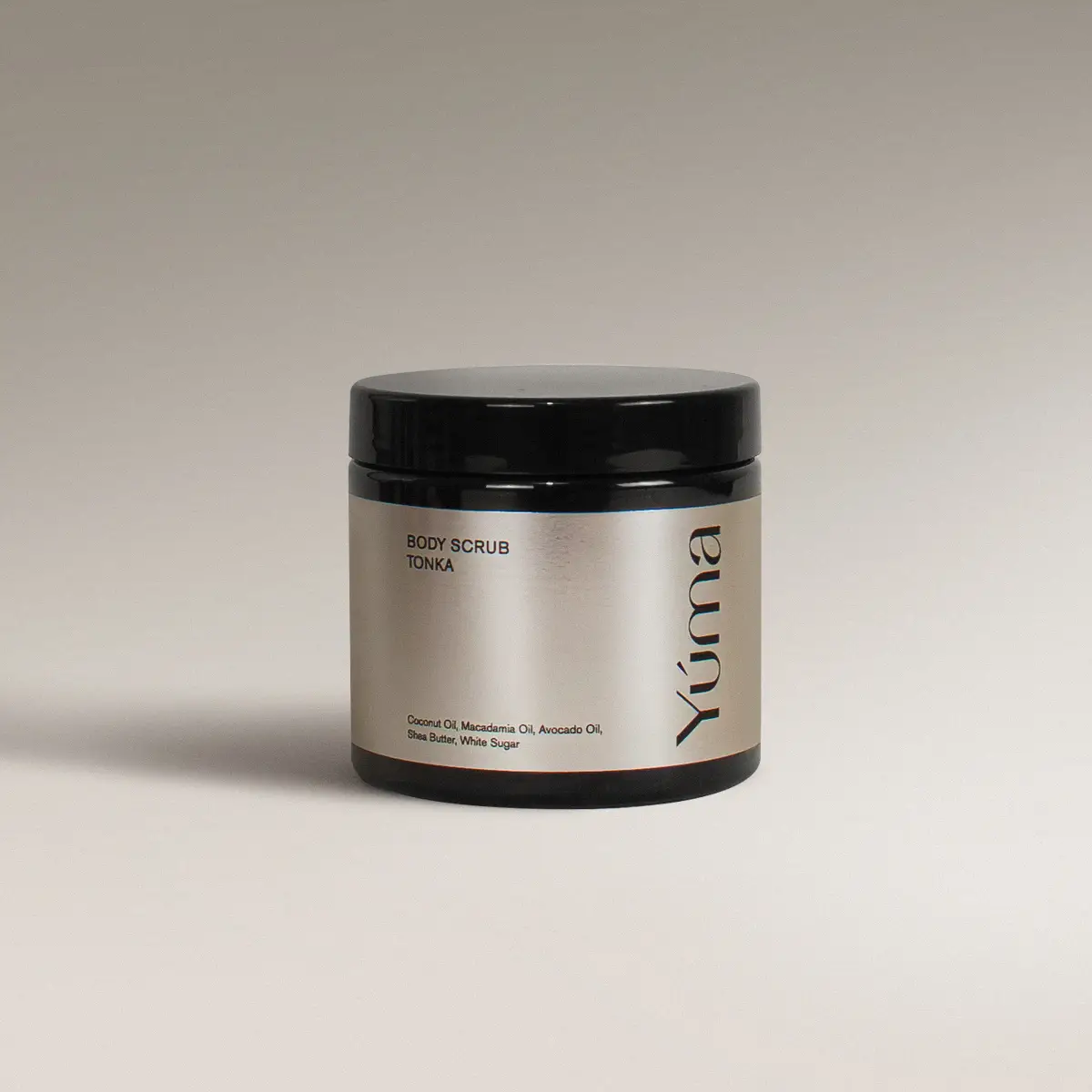 YUMA Tonka scented Body Scrub in a black jar with a silver label on a grey background.