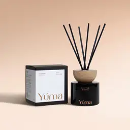 YUMA Oriental Mimosa reed diffuser in a black glass bottle with a wooden stopper, next to its packaging.