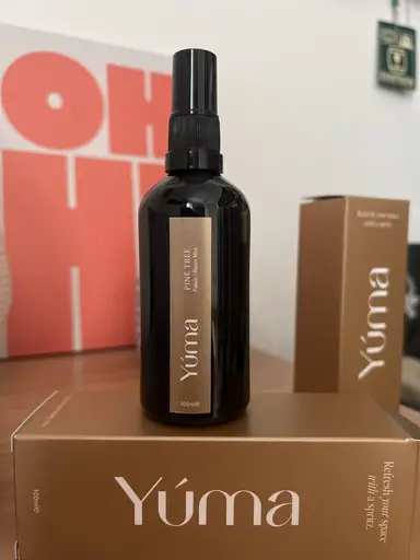 A dark YUMA Pine Tree room spray bottle resting on brown paper packaging.