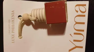 A YUMA Car Diffuser with a red cap and wooden details resting on white packaging.