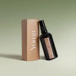 YUMA Fabric Mist Fig Sap dark glass bottle next to its brown paper packaging.