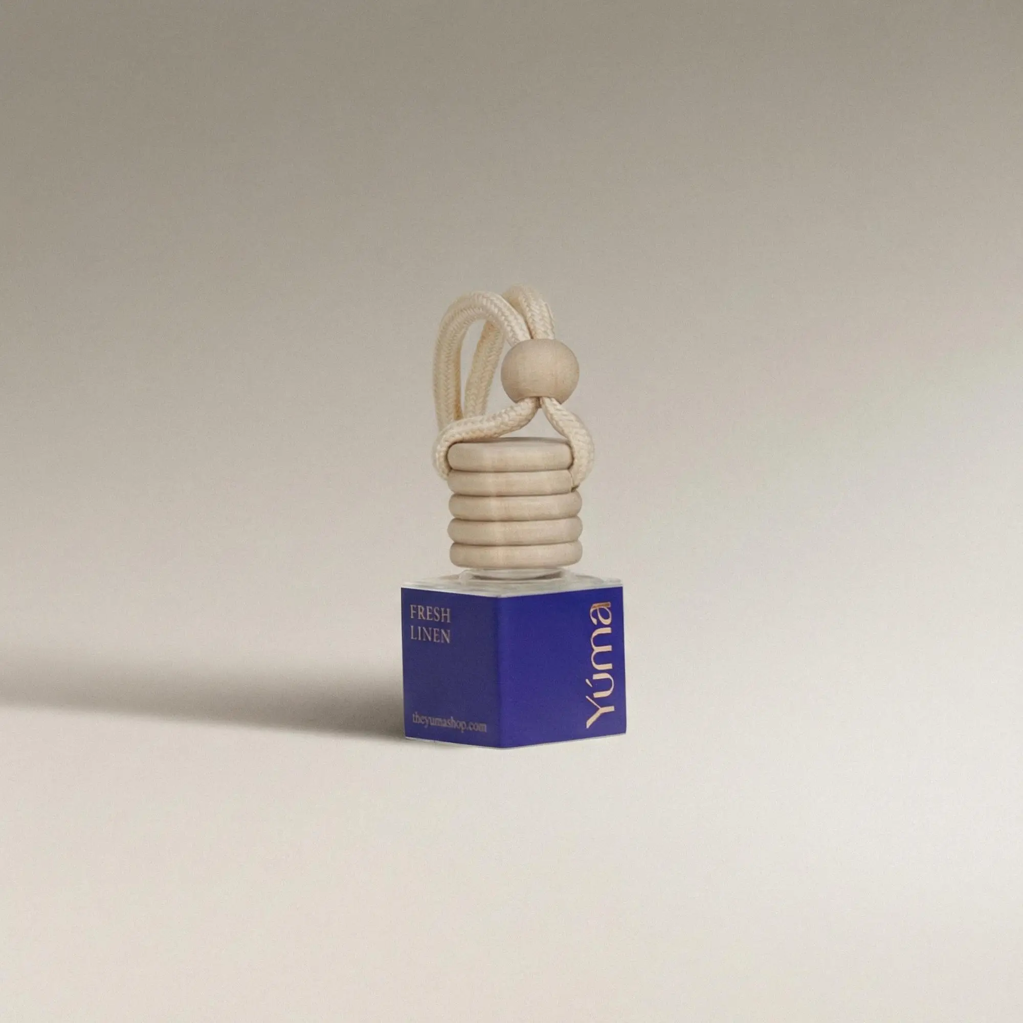 YUMA car diffuser with a blue Fresh Linen label, wooden stopper, and hanging cord.