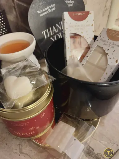 A red YUMA metal tin alongside scented wax melts and a white burner filled with liquid wax.