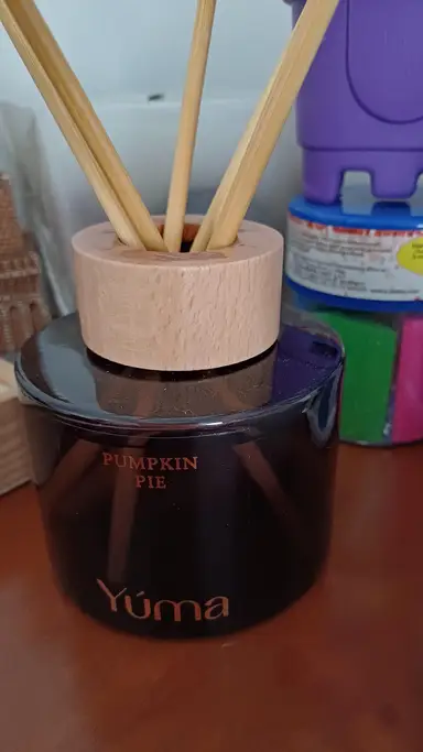 YUMA Pumpkin Pie dark glass room diffuser with a wooden cap and reed sticks.