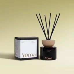 YUMA Eternal Eden reed diffuser in a black glass vessel beside its paper packaging.