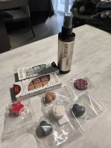 A YUMA spray, two wax melt packages, and an assortment of small scented wax shapes including hearts and flowers.