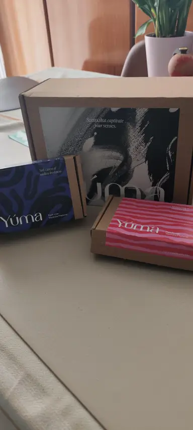 A large YUMA paper box next to two smaller packages with blue and pink designs.