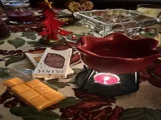 Ceramic wax melt burner with a lit tealight beside YUMA wax melts on a festive tablecloth.