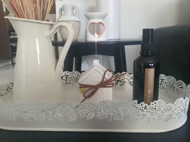 A white tray styled with a small jug, a decorative house figurine, and a black bottle of YUMA Velvet Cashmere.
