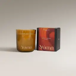 YUMA Salted Caramel candle in an amber glass vessel beside its paper packaging.