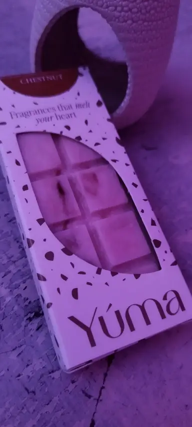 YUMA wax melts in a chocolate-bar shape next to a ceramic fragrance warmer, lit in purple light.