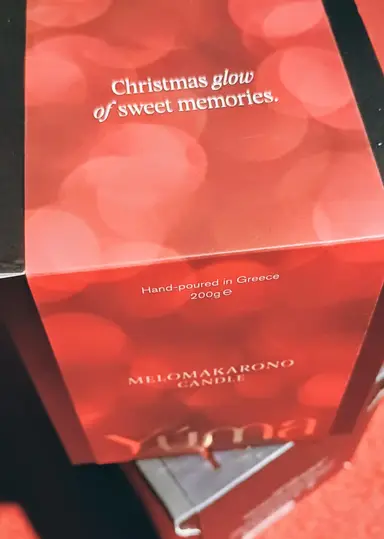 Red box for the YUMA MELOMAKARONO CANDLE with a bokeh effect and white lettering.