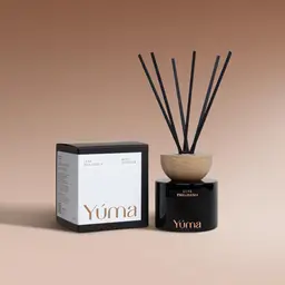 YUMA Luxe Philoxenia reed diffuser in a black glass vessel next to its packaging.
