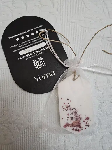 White YUMA wardrobe sachet with dried petals in a pouch next to a black YUMA card.