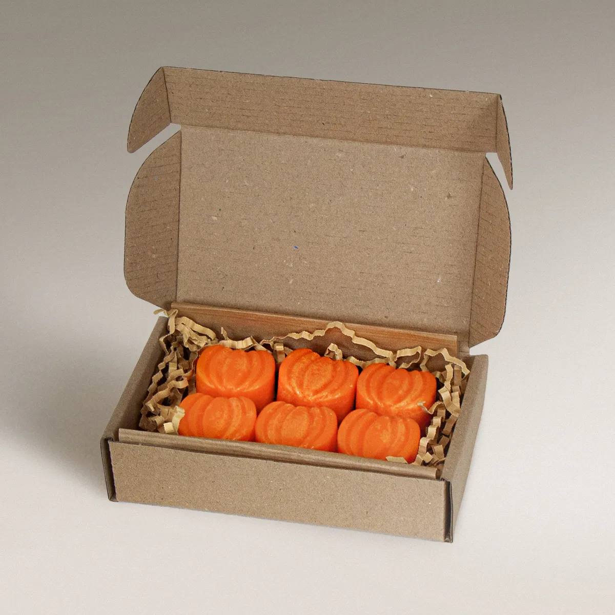 Six pumpkin-shaped Pumpkin Pie wax melts in orange, displayed inside an open cardboard box.