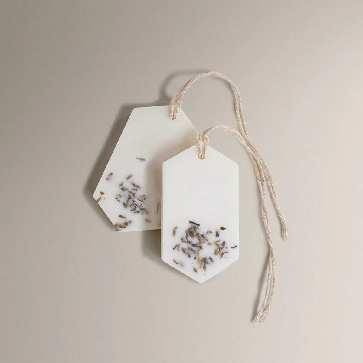 Two white Gold Orchid Wax Tablets with dried flowers and twine on a beige background.
