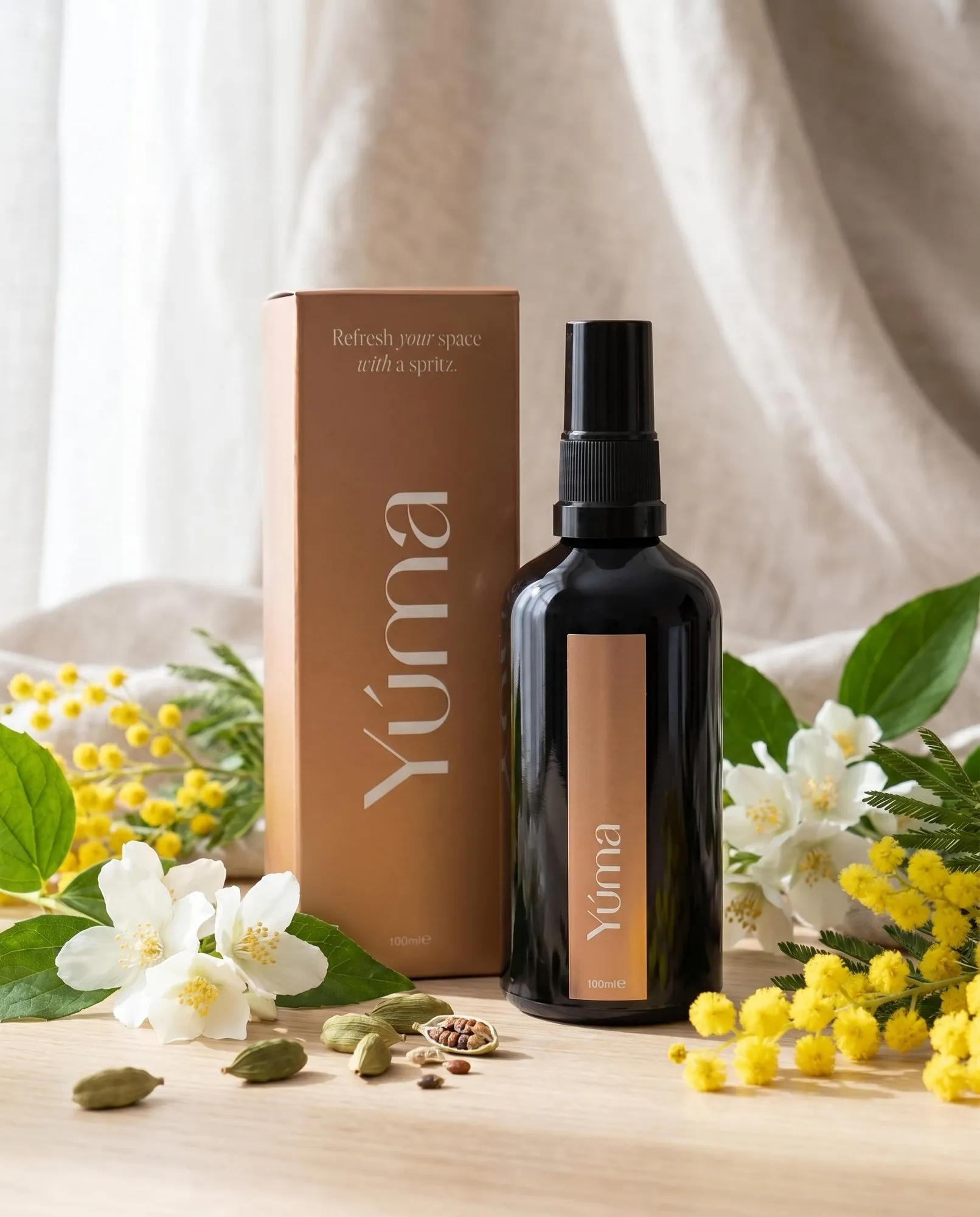 YUMA Oriental Mimosa black fabric spray bottle beside paper packaging, white flowers, and mimosa blooms.