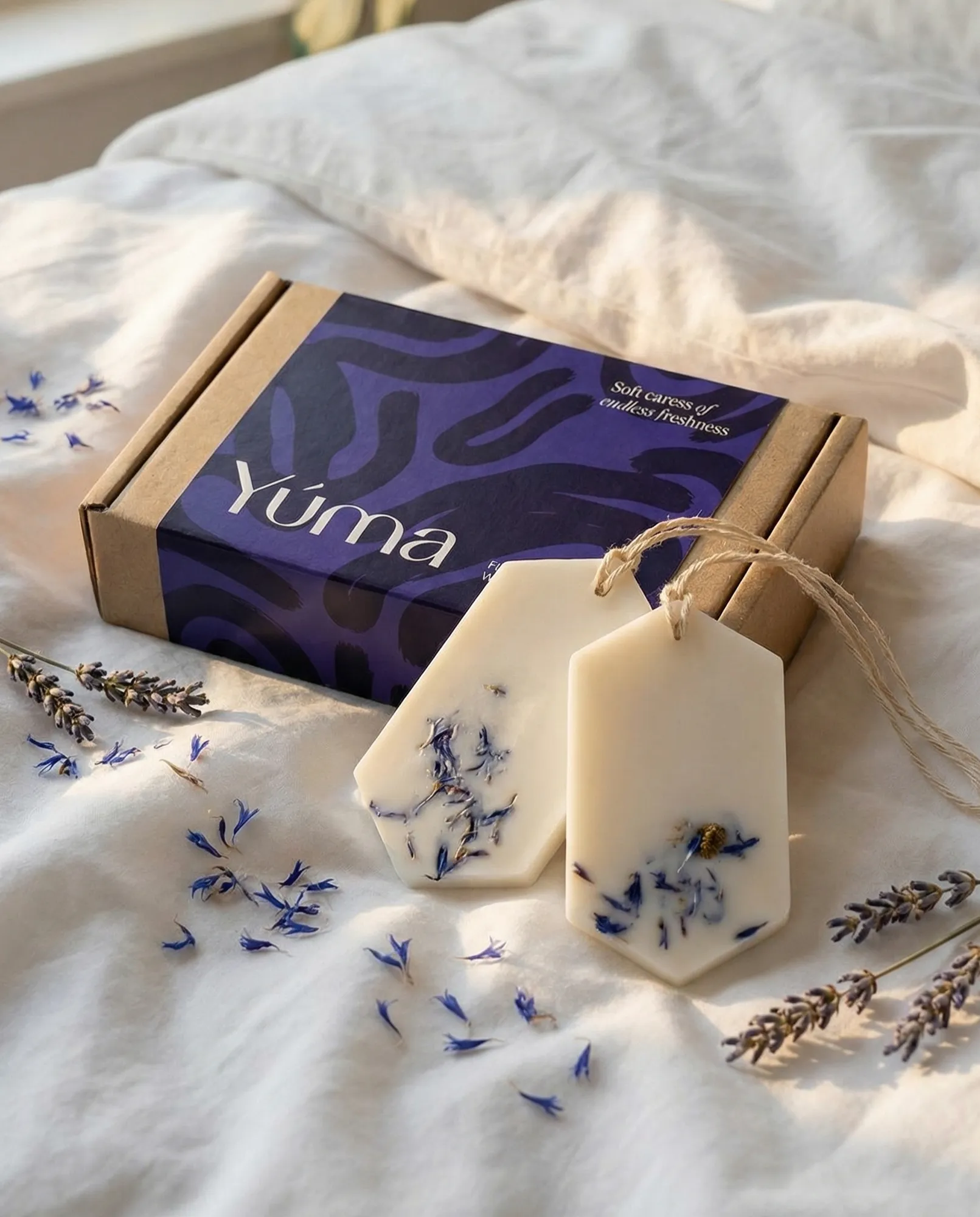Two white Fresh Linen Wax Tablets with dried flowers on white bed linen.