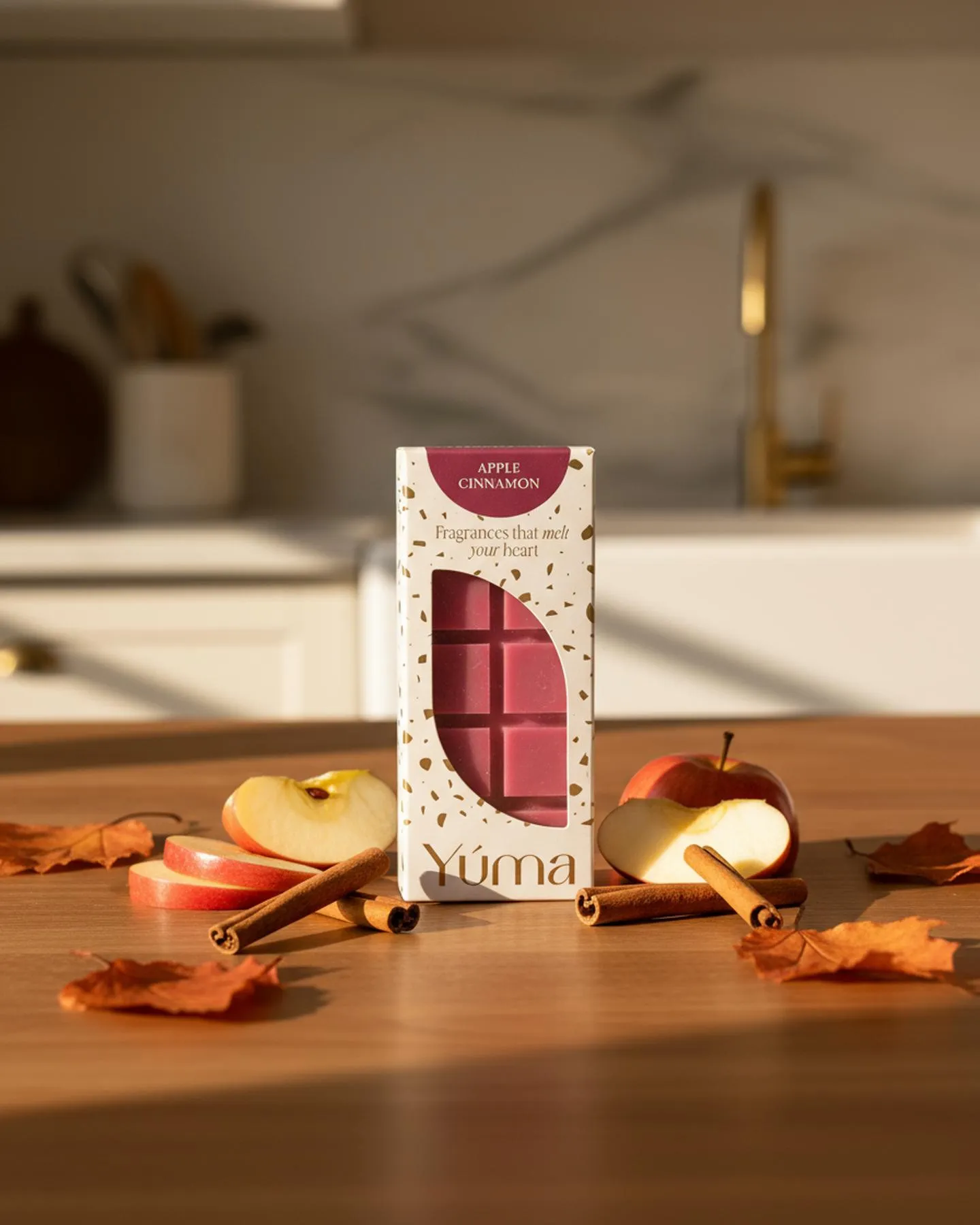 YUMA Apple Cinnamon wax melts packaging surrounded by apple slices, cinnamon sticks, and autumn leaves.
