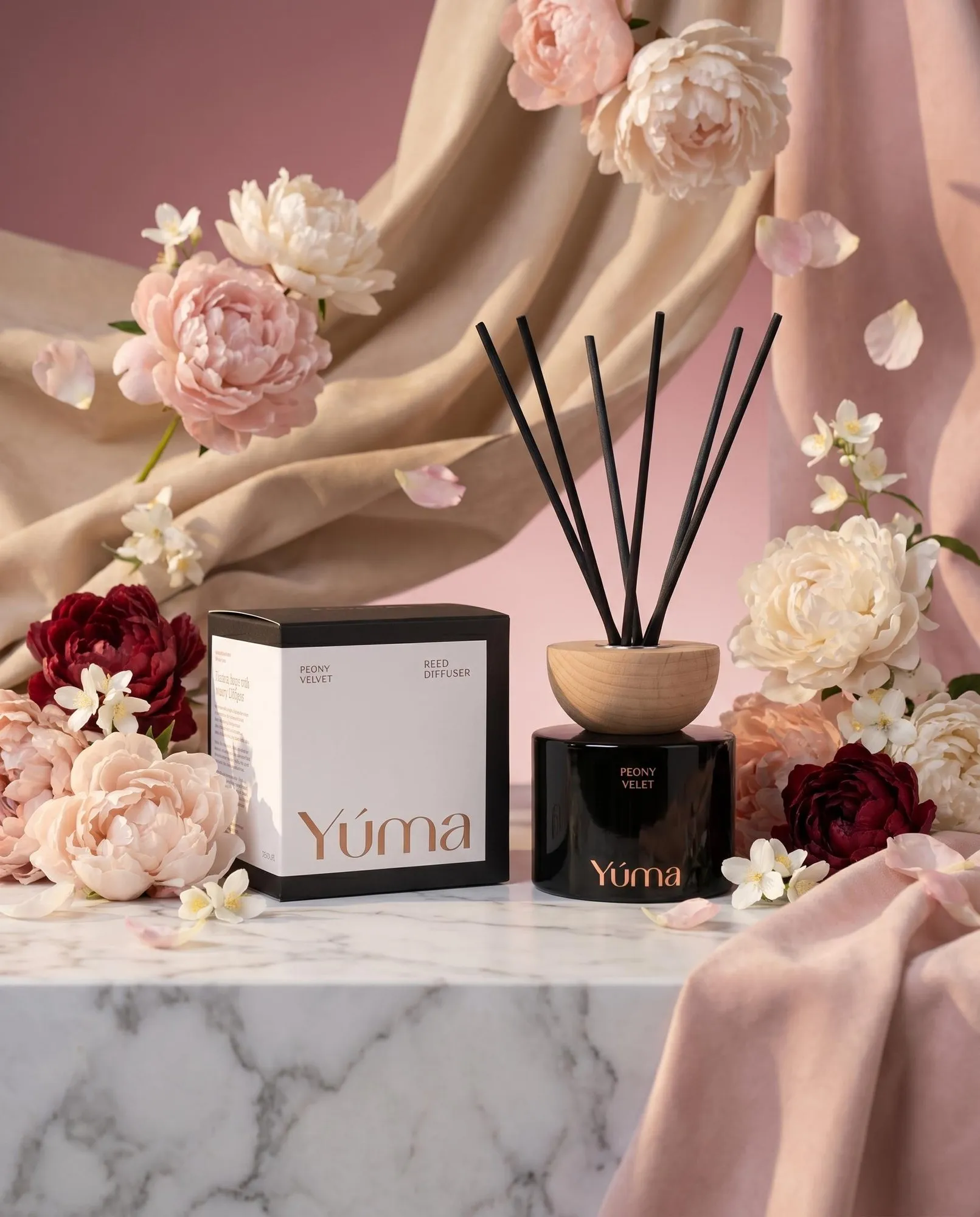 YUMA Peony Velvet reed diffuser in a black vessel beside its packaging, with peonies in the background.