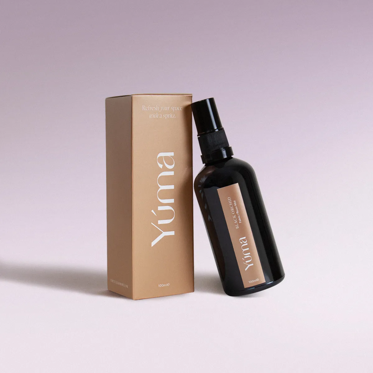 YUMA Black Orchid fabric mist in a black bottle next to its beige paper packaging.