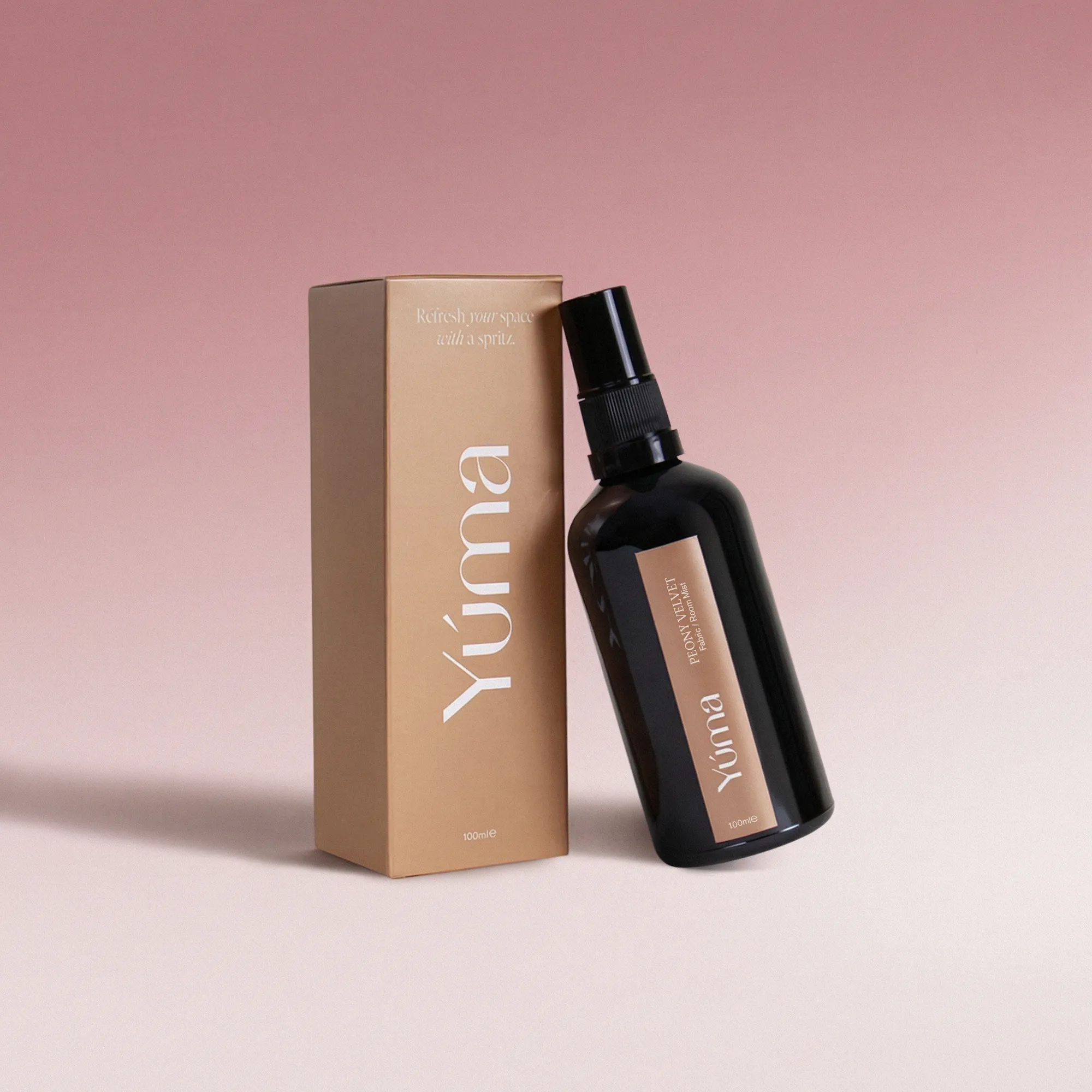 A black YUMA Peony Velvet Fabric Mist bottle next to its beige paper packaging.