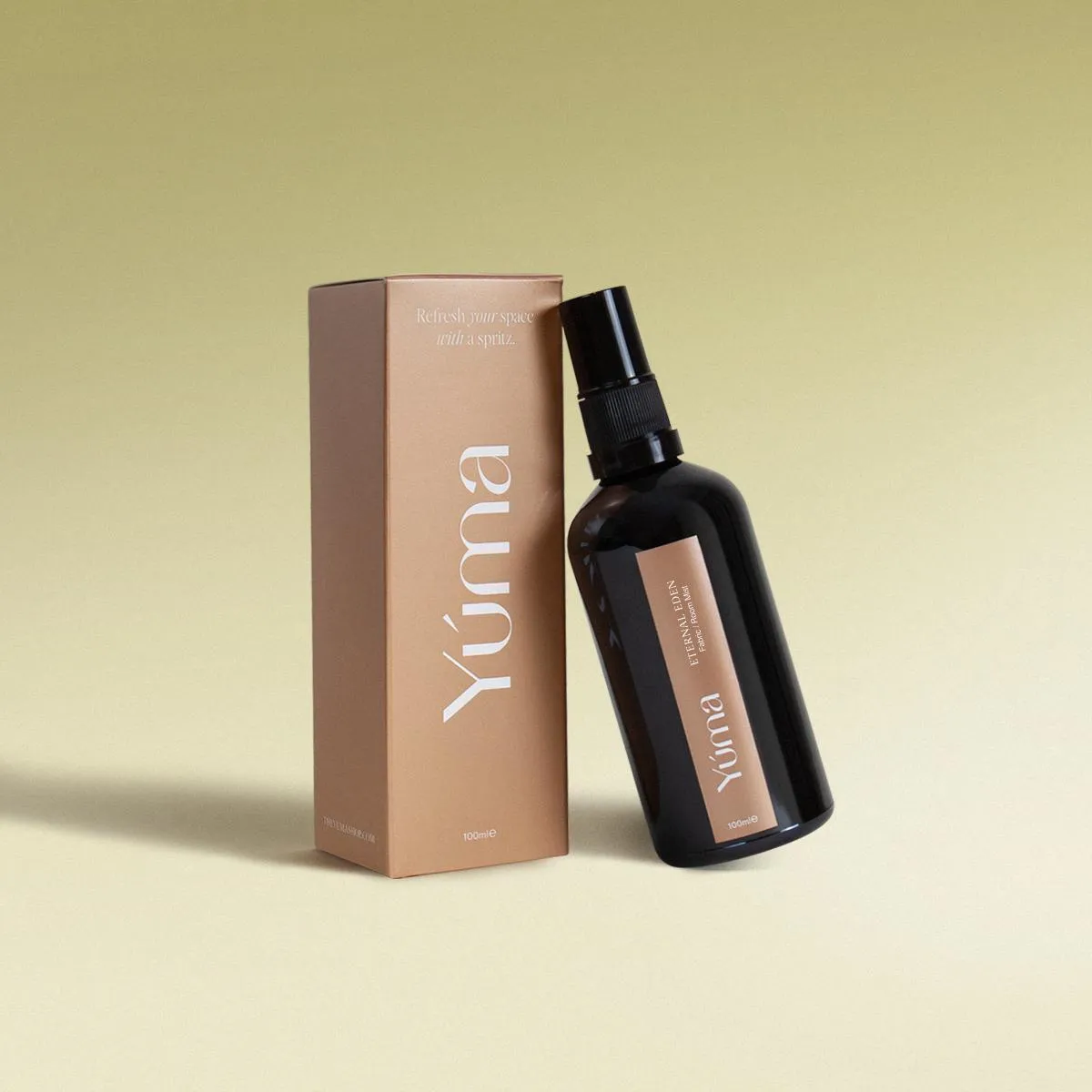 YUMA Eternal Eden Fabric Mist in a dark glass bottle next to its beige paper packaging.